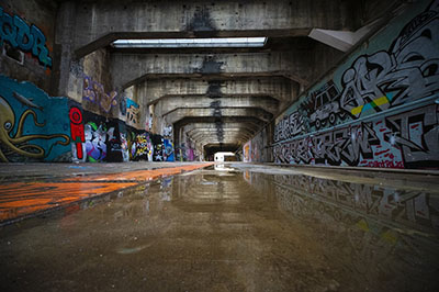 Eine lange überdachte Durchfahrt. An den Wänden sind Graffitis gesprüht.